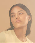 Woman with earrings against a warm beige background