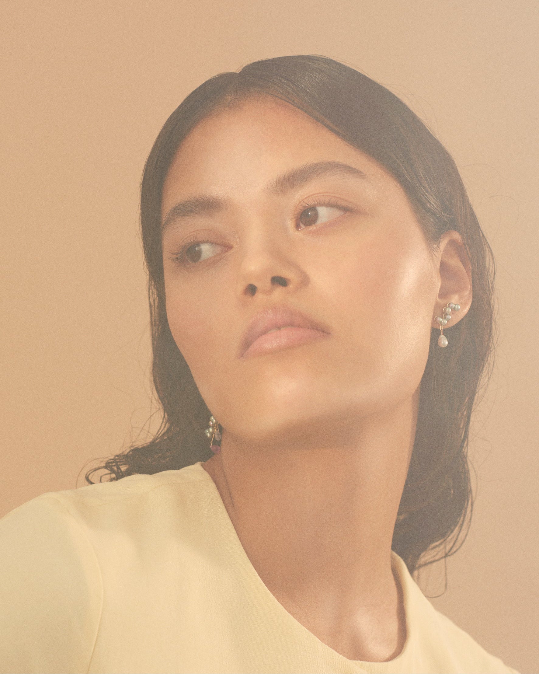 Woman with earrings against a warm beige background
