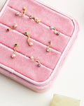 Gold and pearl earrings on a pink jewelry case