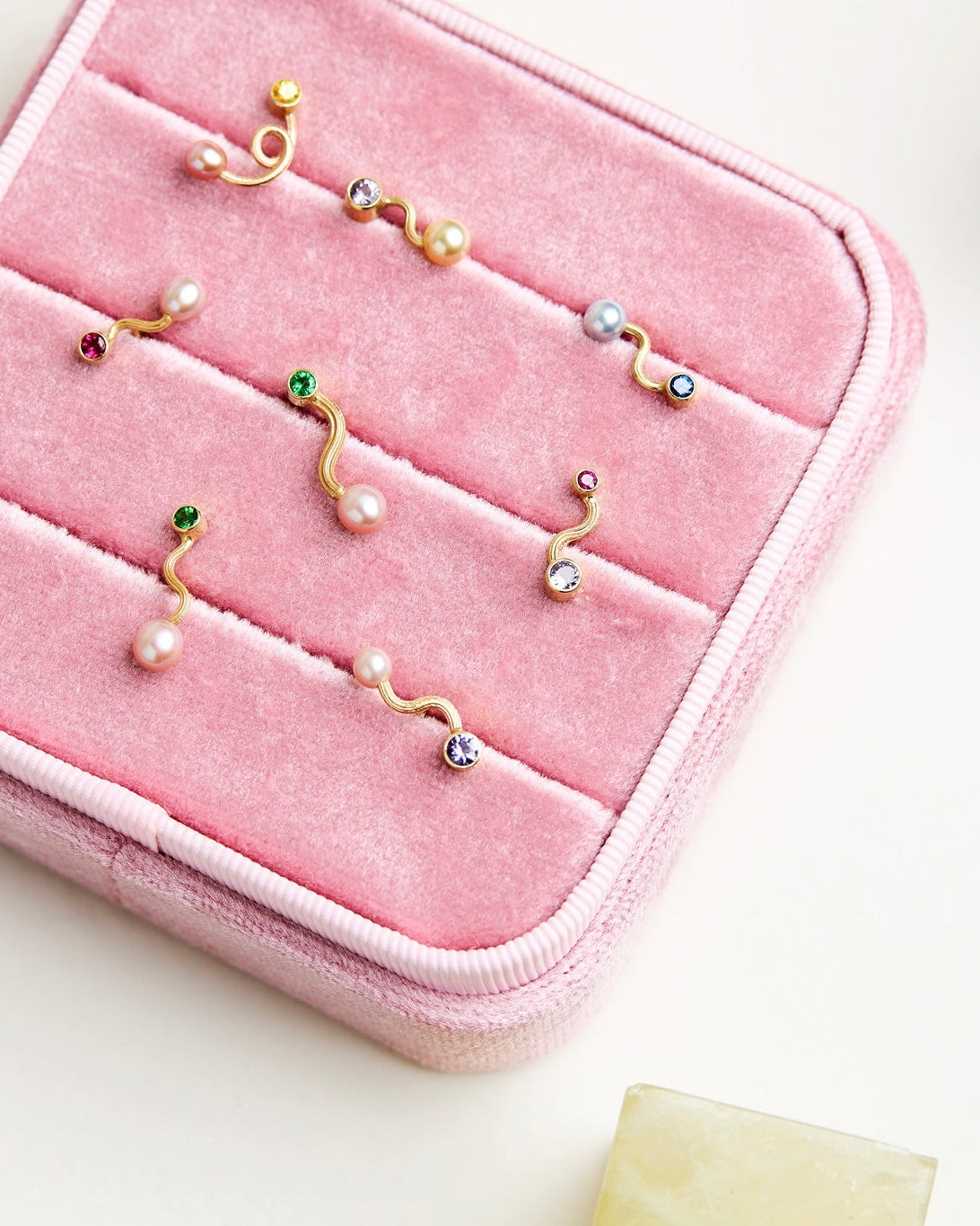 Gold and pearl earrings on a pink jewelry case