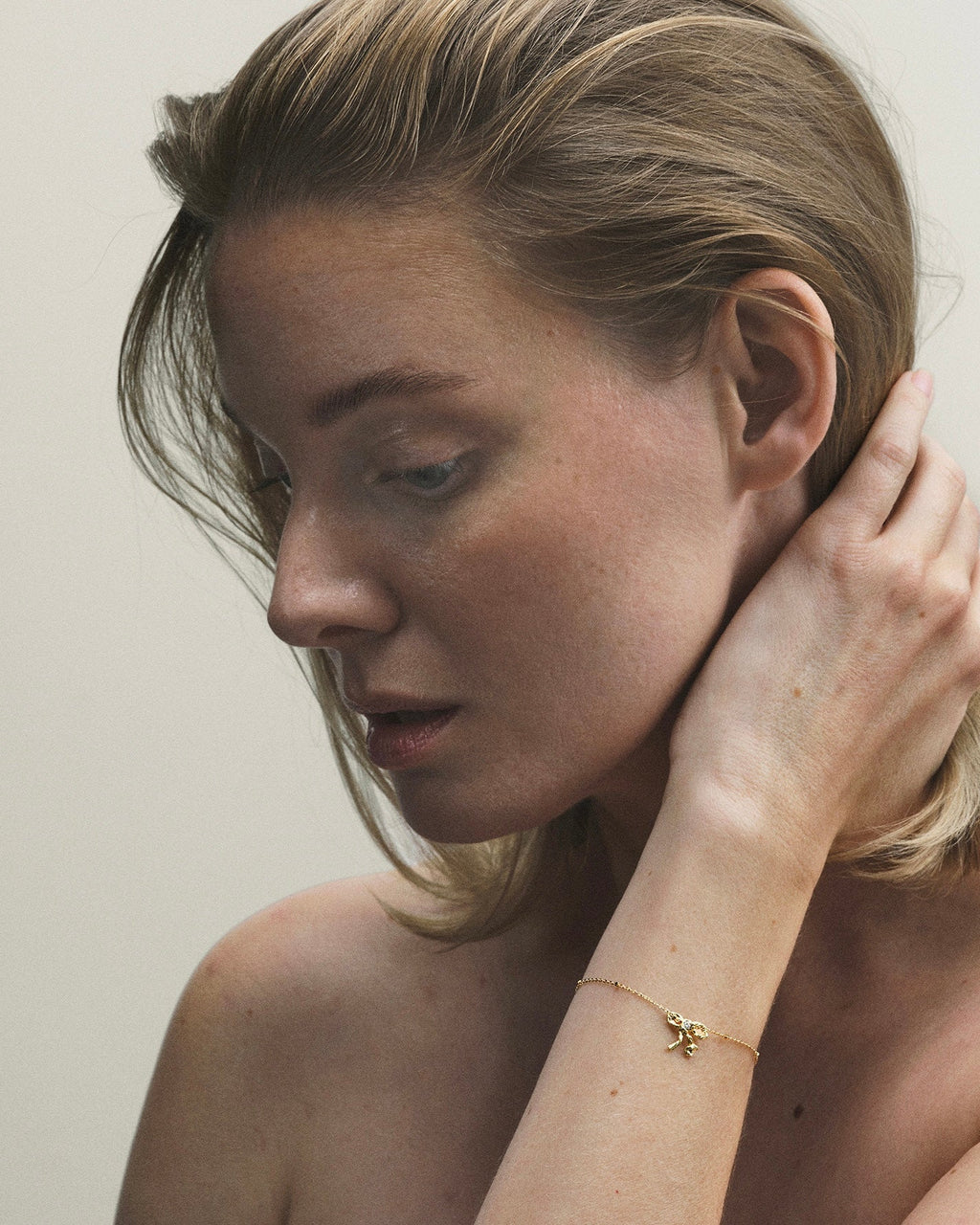 A person wearing a gold bracelet with a small diamond on their wrist.