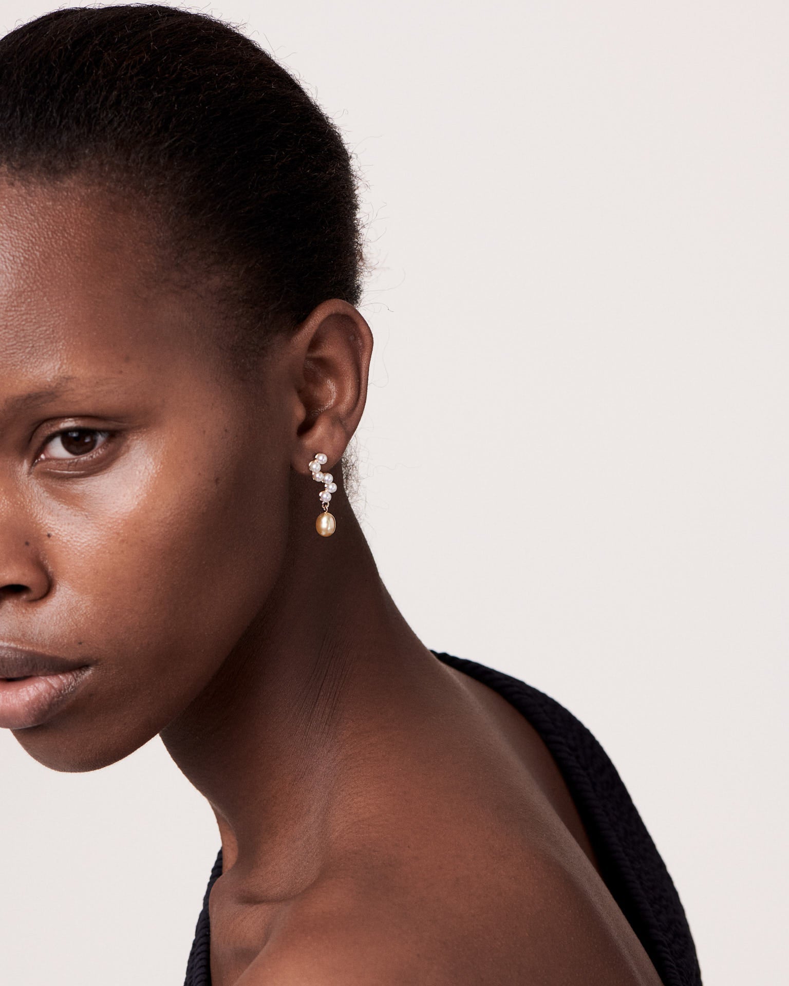Close-up of a woman wearing earrings against a plain background