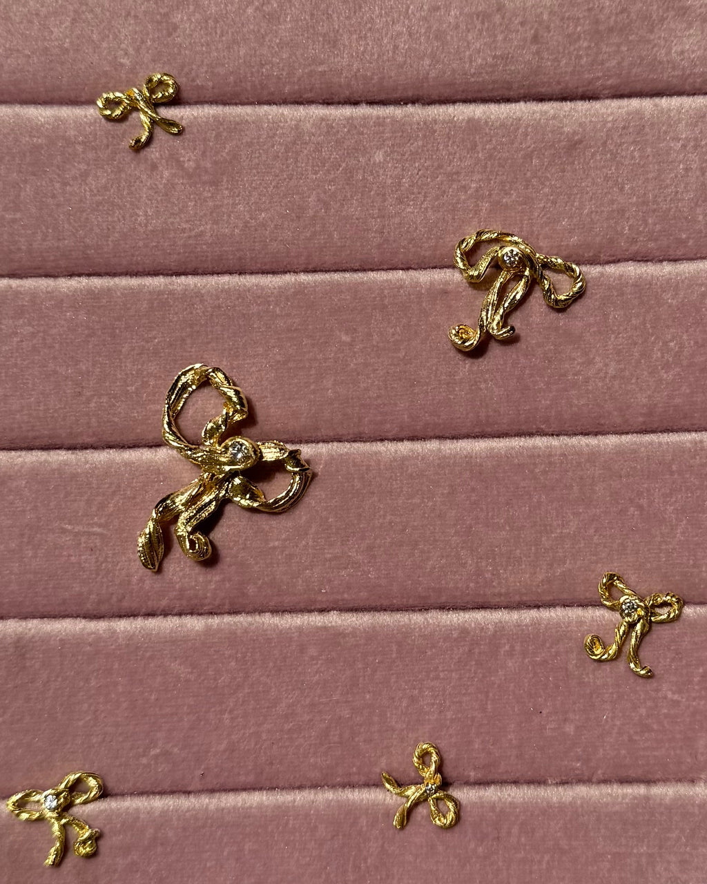 Gold bow-shaped charms on a pink velvet surface