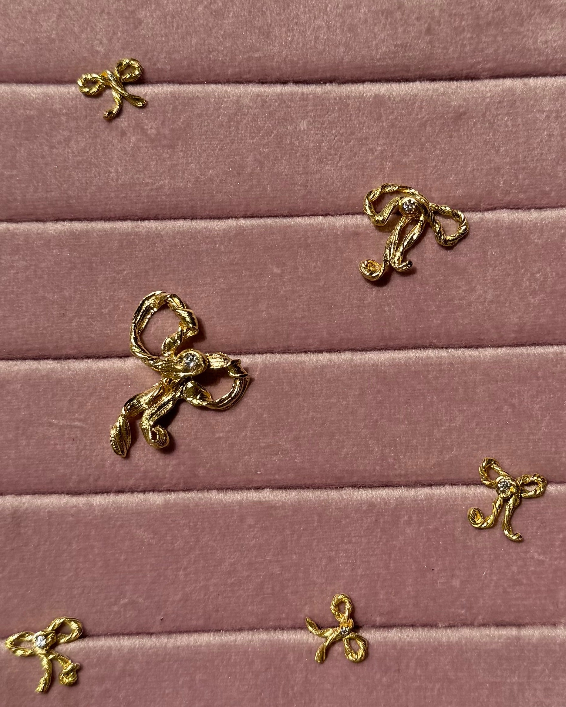 Gold bow-shaped charms on a pink velvet surface