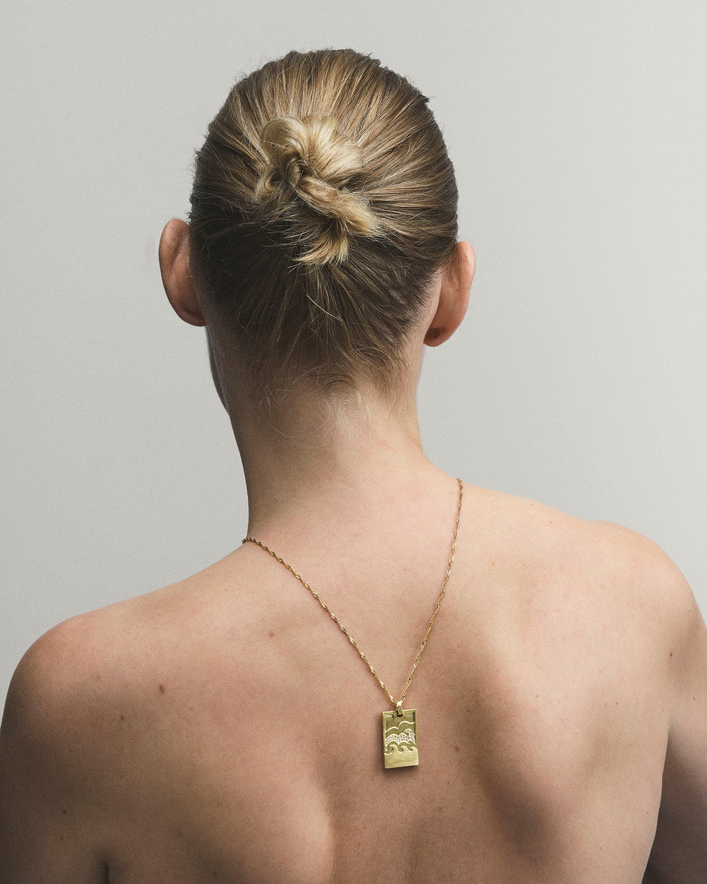 Person with a gold necklace on a plain background