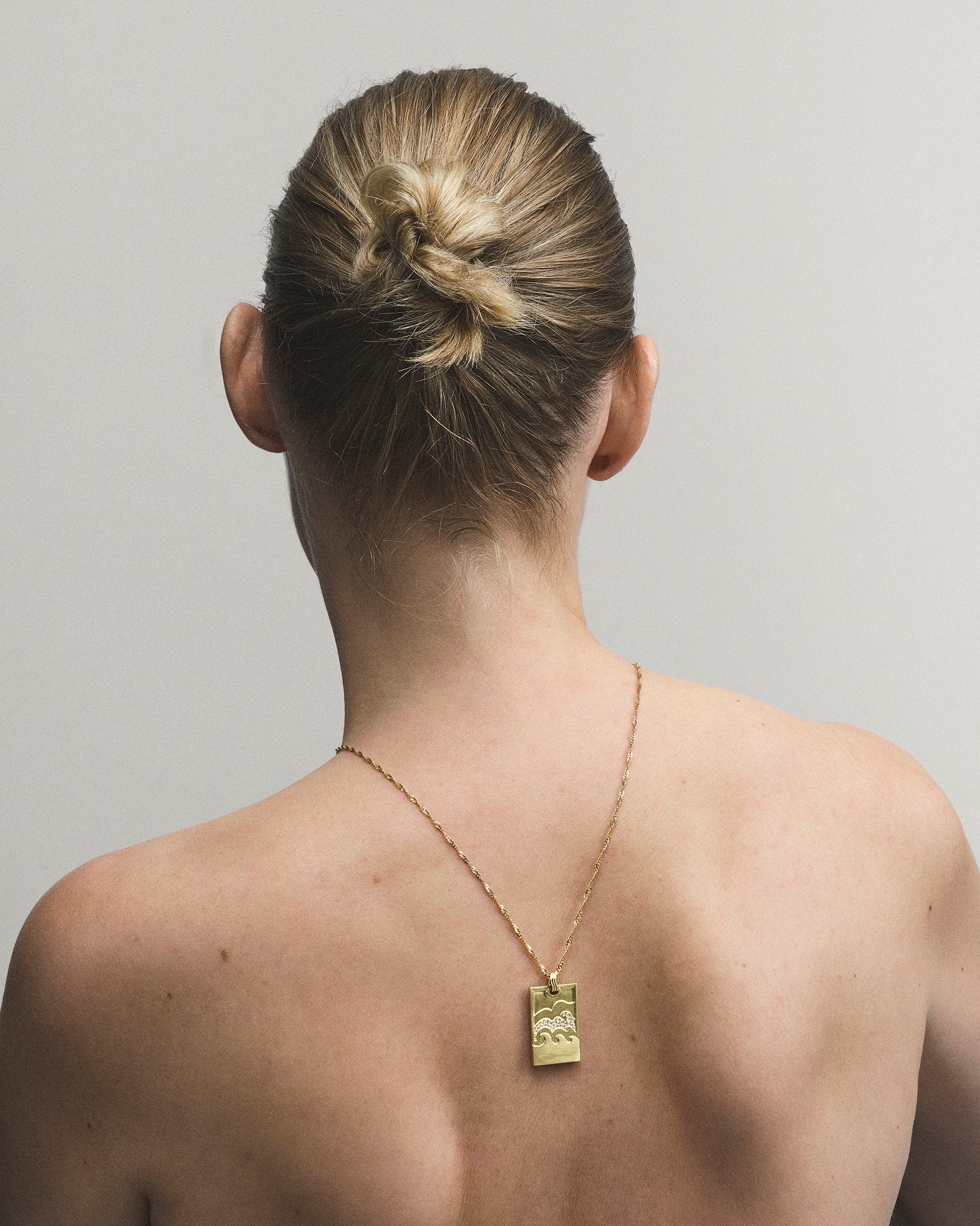 Person with a gold necklace on a plain background