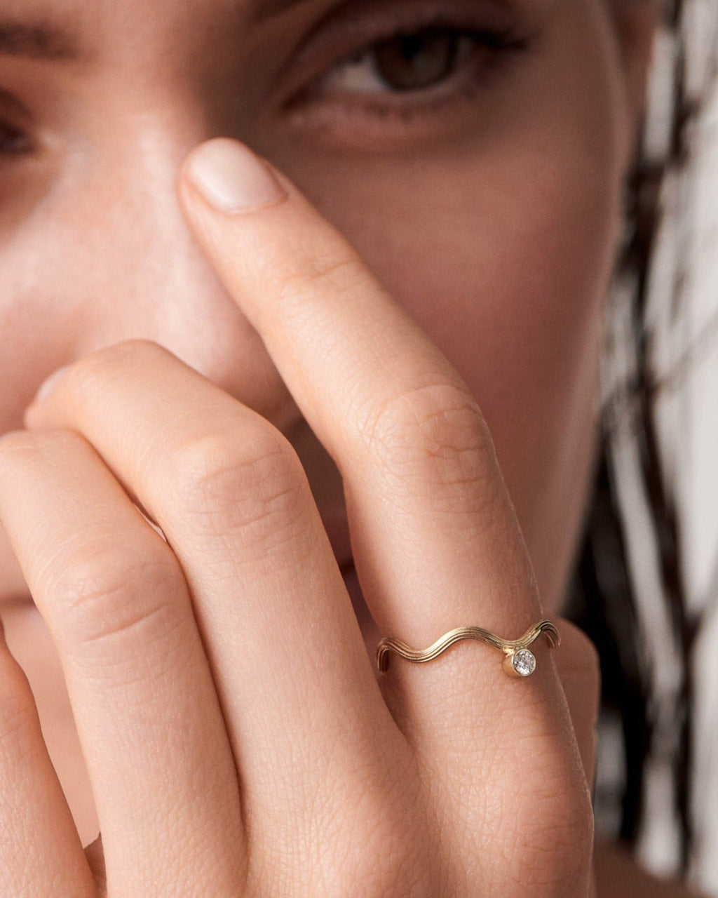 A close-up image of a person's finger showcasing a gold ring with a small, round diamond on it.